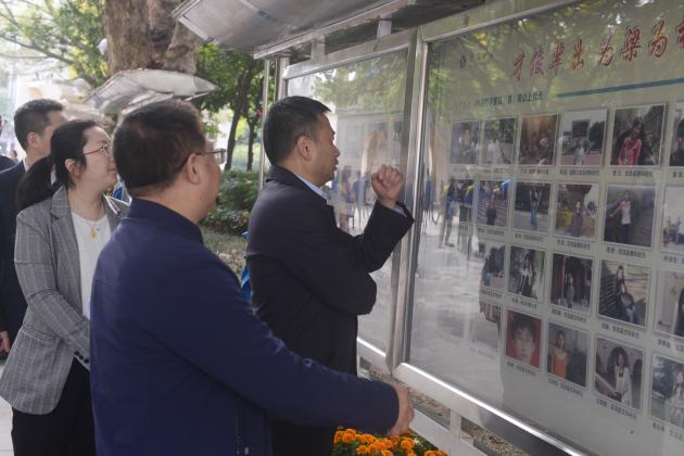 王毅部长一行在龙校长的带领下参观校园，在学校状元榜前驻足