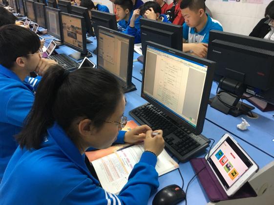  学生使用电脑、平板、教材等工具完成课堂任务