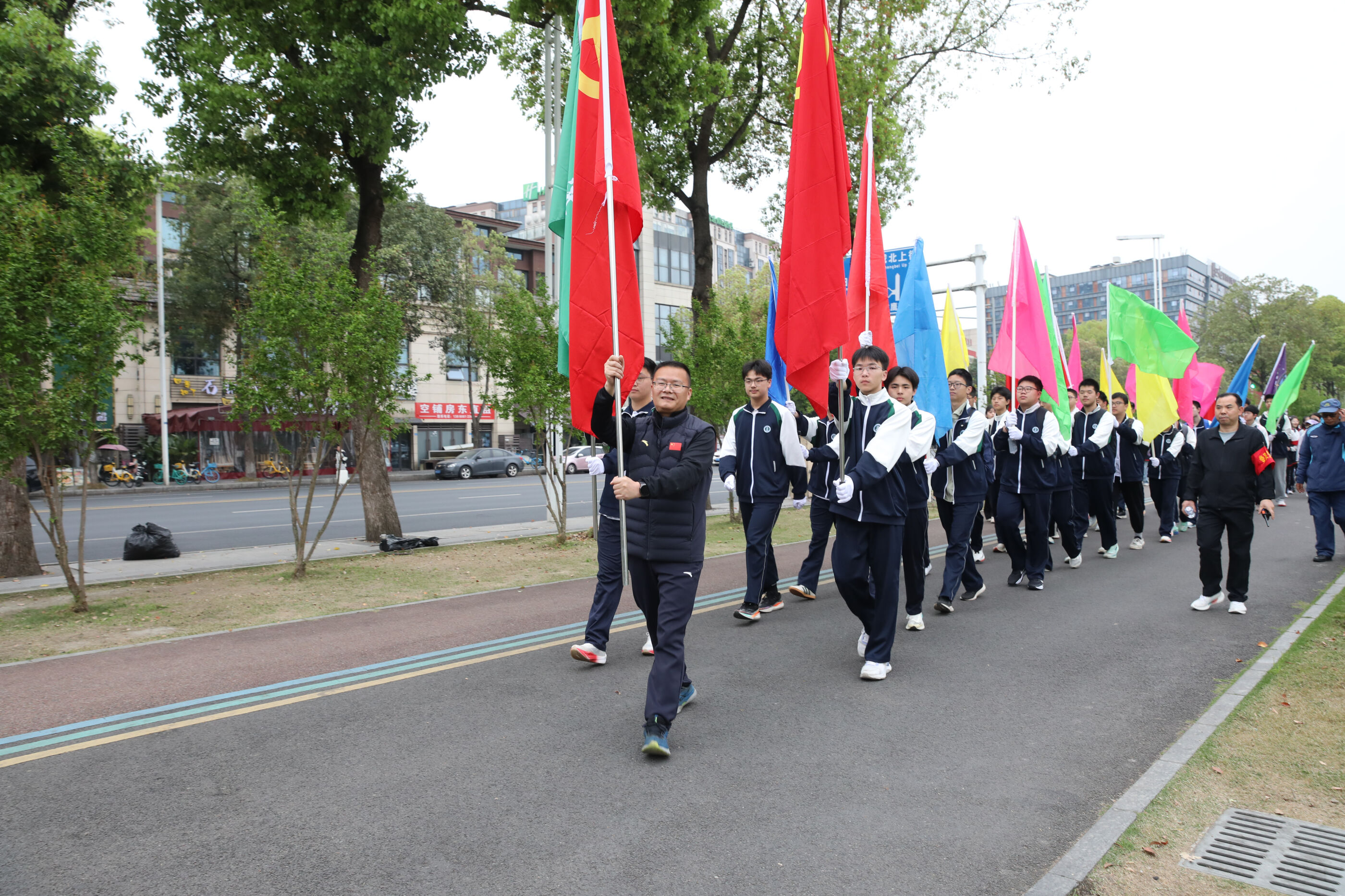 以双流中学党委书记为首的彩旗方队引领队伍前进
